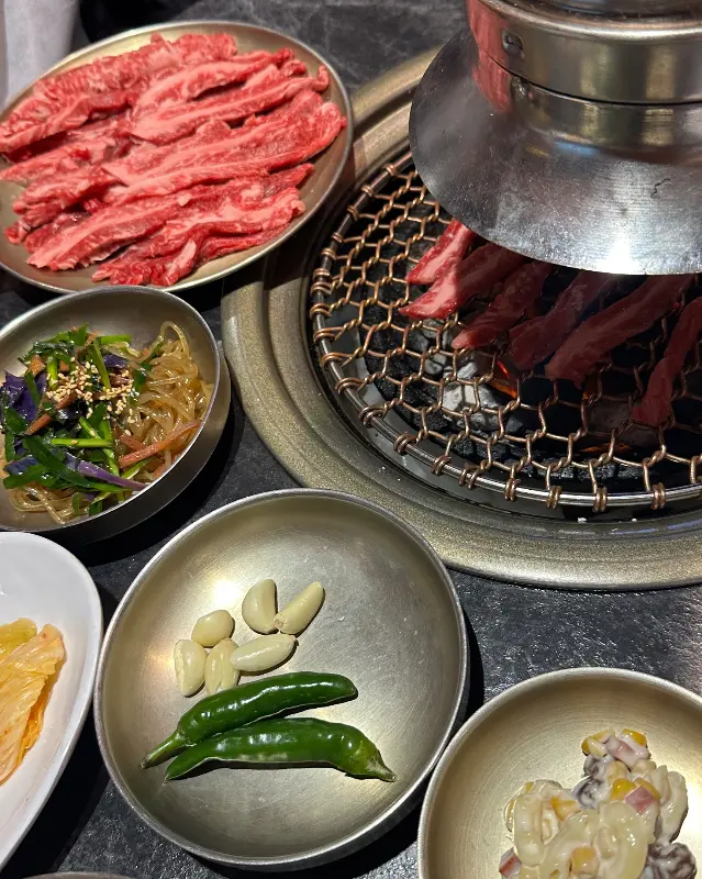 숯불 위에서 지글거리는 갈비살과 풍성한 밑반찬