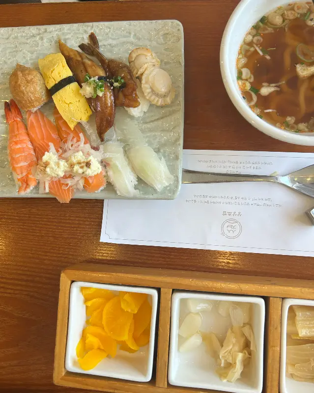 싱싱한 초밥과 따뜻한 우동, 곁들임 반찬이 정갈하게 담겨 있는 런치 세트