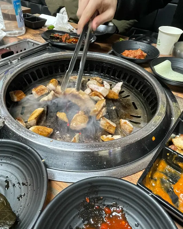 잘 익은 삼겹살을 젓가락으로 집어 올리는 모습