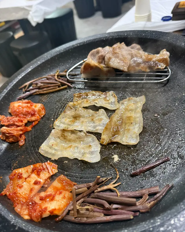 불판 위에서 노릇하게 익어가는 삼겹살과 김치의 조화