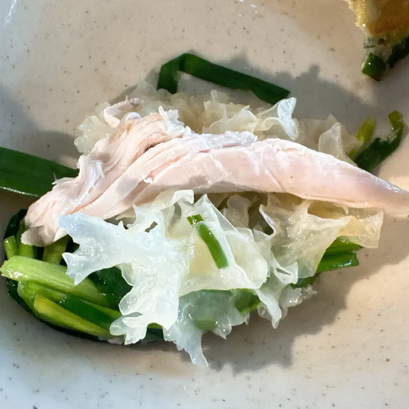 닭고기를 백목이버섯, 부추와 함께 싸서 먹는 모습