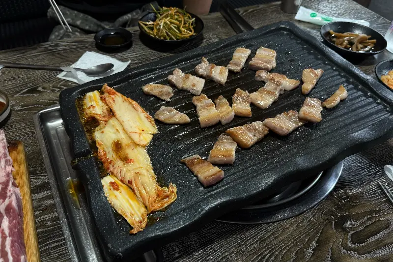 불판 위의 삼겹살과 김치, 콩나물