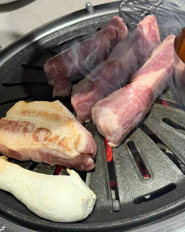 불판 위에서 맛있게 익어가는 두툼한 삼겹살