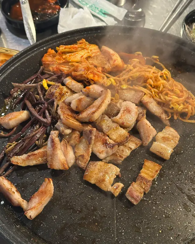 불판 가득 삼겹살과 김치, 콩나물, 고사리를 올려 구워먹는 모습