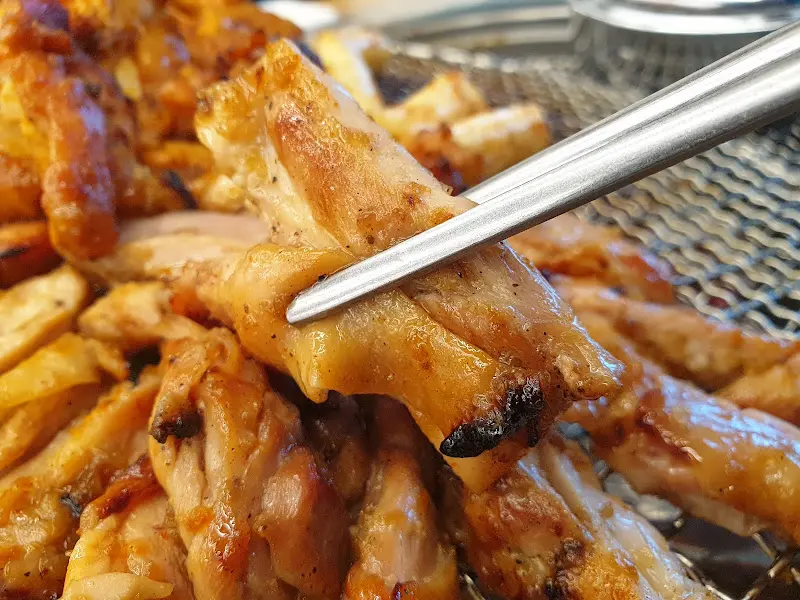 젓가락으로 집어 올린 윤기가 자르르 흐르는 간장 닭갈비