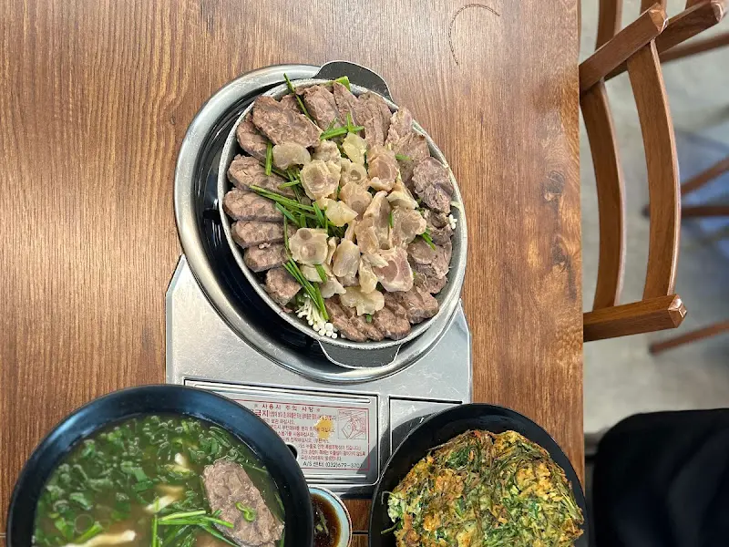 도가니와 수육이 푸짐하게 담겨 있고, 그 위에 초록색 부추가 얹어져 있는 수육전골의 모습