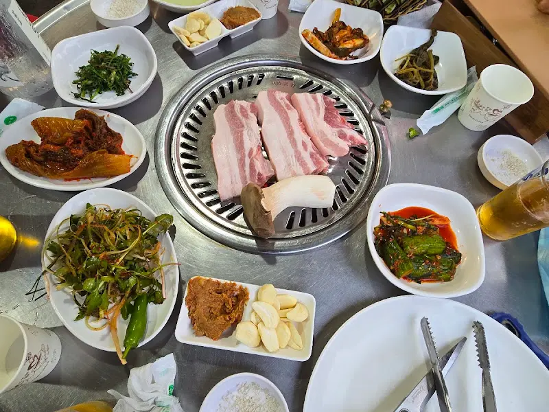 불판 위에 놓인 삼겹살과 주변 반찬