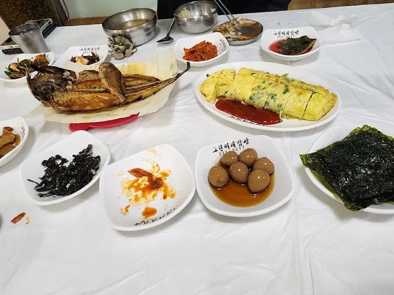 고등어 구이, 계란말이, 김, 나물 등 다양한 반찬이 차려진 모습