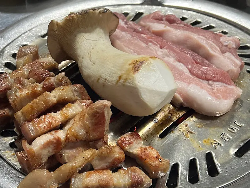 불판 위에서 구워지고 있는 삼겹살과 버섯