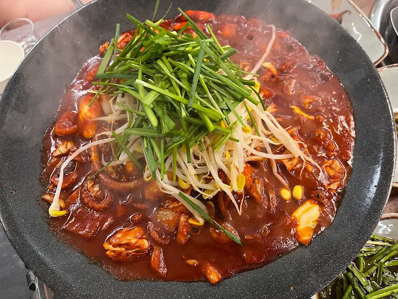 매콤한 양념에 볶아진 낙지볶음 위에 싱싱한 부추와 콩나물이 듬뿍 올려져 있는 모습