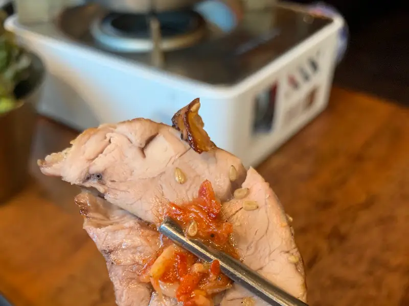 젓가락으로 집은 보쌈 위에 김치를 올려놓은 모습