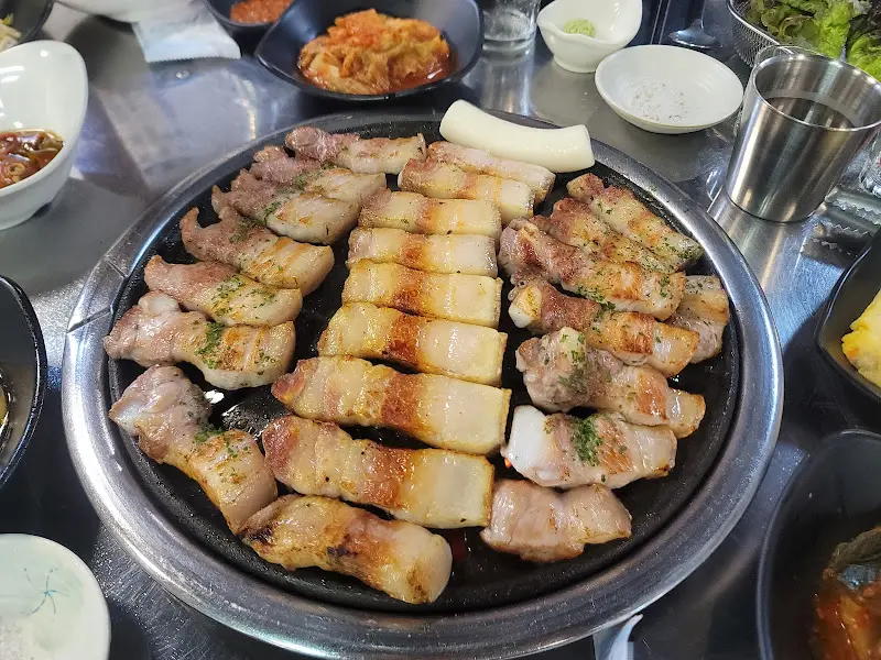 잘 구워진 오겹살이 불판 위에 가득 담겨 있다.