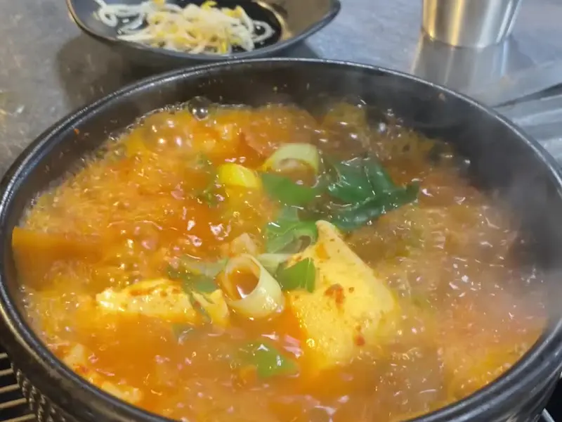뚝배기 안에서 보글보글 끓고 있는 김치찌개의 모습이 담겨 있다.