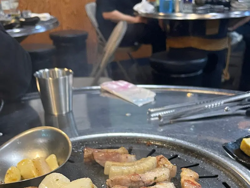 불판 위에 가지런히 놓인 초벌구이 오겹살의 모습이 보인다.