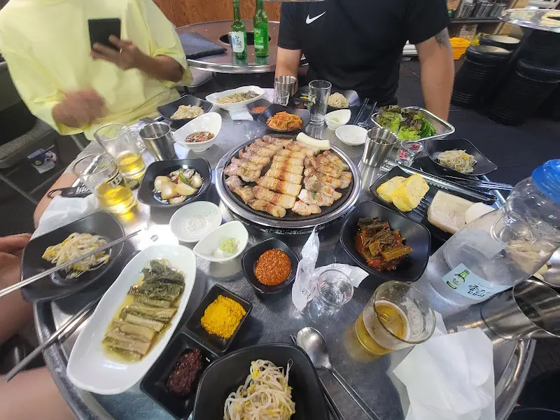 테이블 가득 차려진 오겹살과 다양한 반찬들의 모습이 보인다.