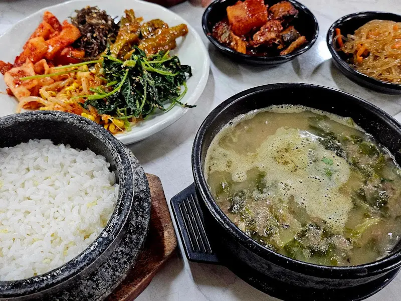 돌솥밥과 추어탕, 그리고 다양한 반찬들이 차려진 테이블 모습