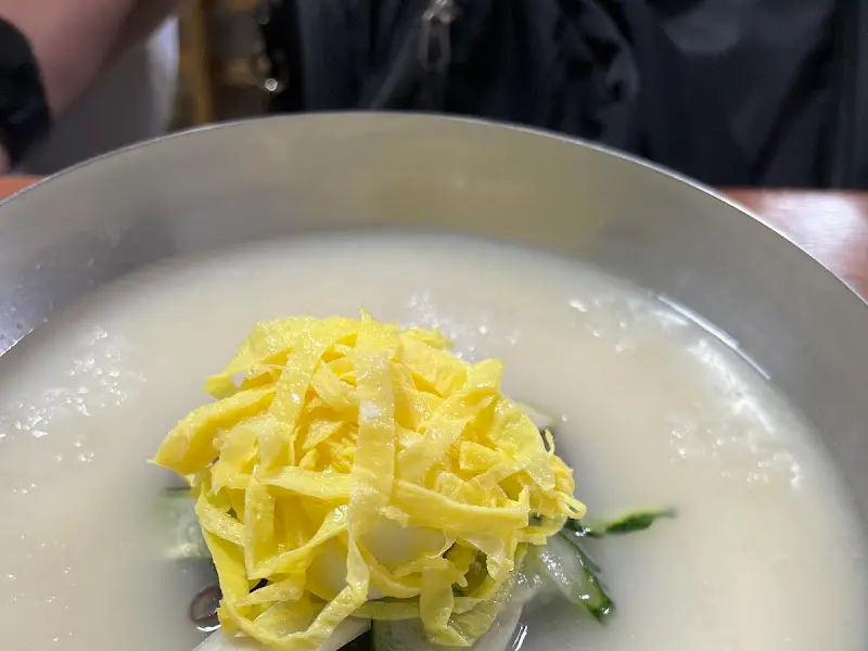 뽀얀 사골 육수 위에 고명이 올려진 물냉면