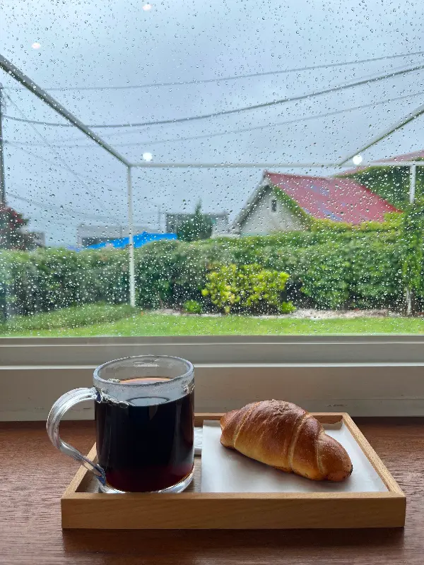 창밖으로 비가 내리는 풍경을 바라보며 커피를 마시는 모습