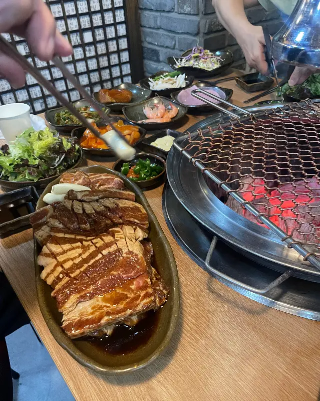 숯불 위에 올려진 돼지갈비와 풍성한 밑반찬