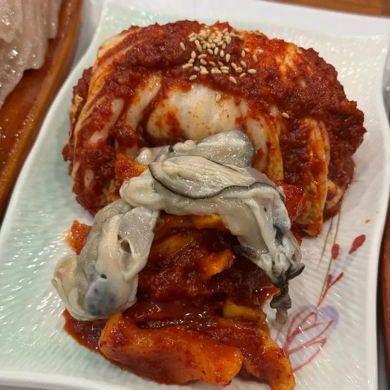 붉은 양념이 인상적인 보쌈김치 위에는 신선한 굴이 올려져 있다.