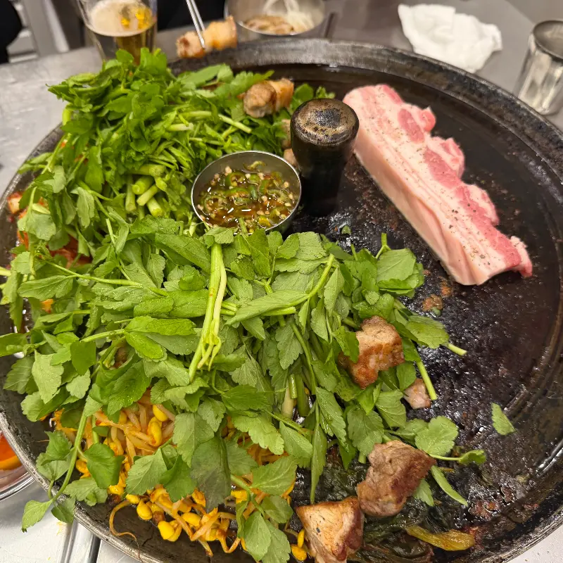 솥뚜껑 위에서 익어가는 목살과 미나리