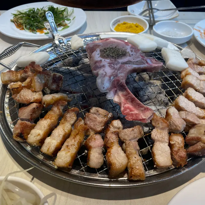 숯불 위에서 삼겹살과 떡을 함께 굽는 모습