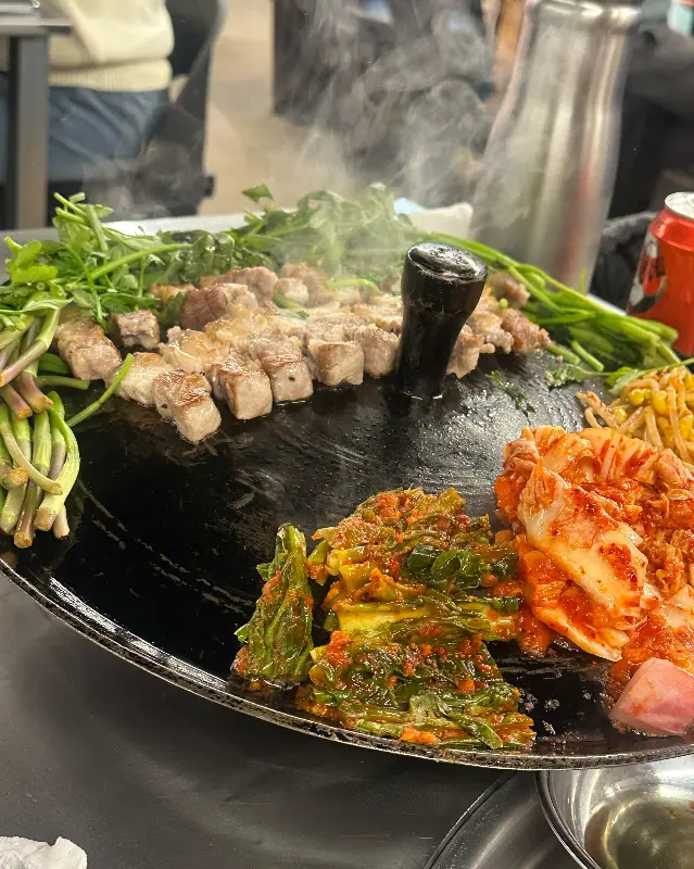 솥뚜껑에 구워진 삼겹살과 김치