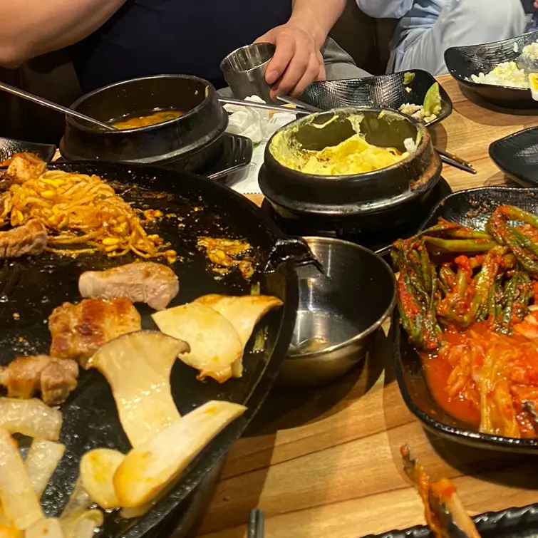 솥뚜껑 위에 구워진 삼겹살과 계란찜, 김치 등의 모습