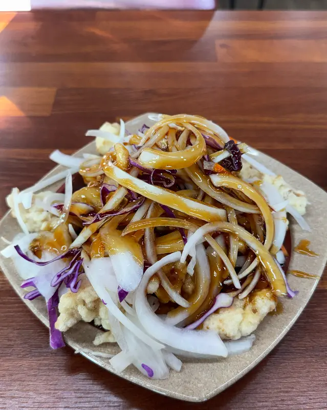 탕수육 위에 소스가 뿌려져 있고, 양파와 양배추가 곁들여진 모습