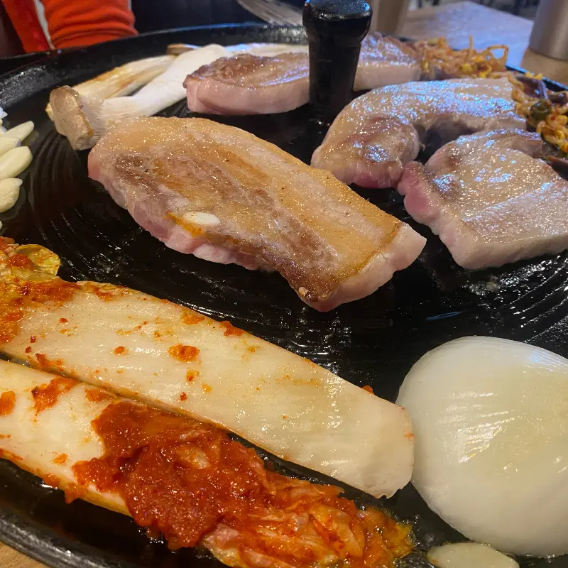 두툼하게 썰린 삼겹살이 솥뚜껑 위에서 익어가는 모습