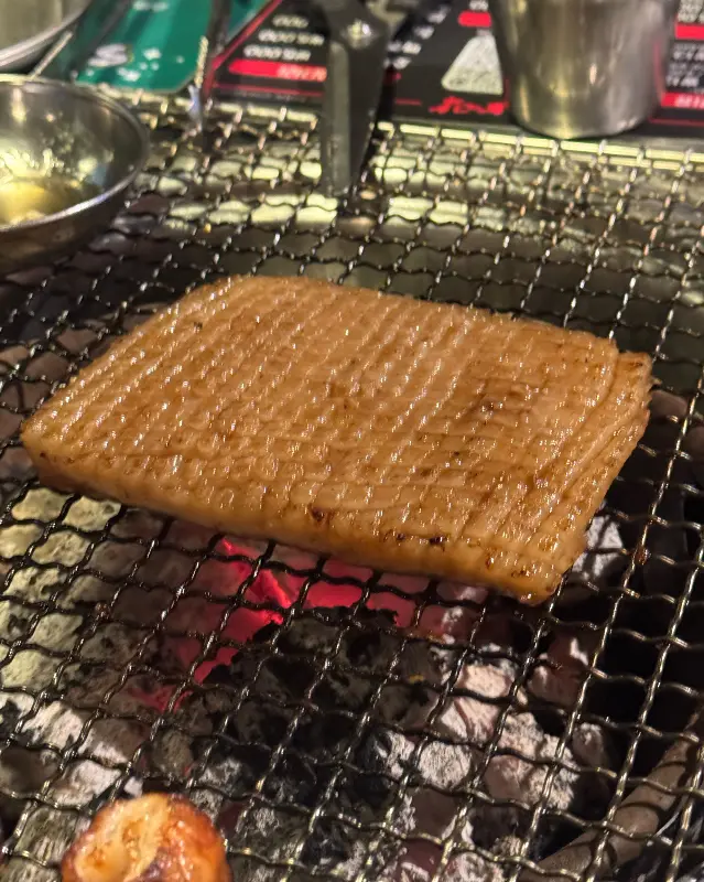 두툼한 돼지 껍데기가 불판 위에서 맛있게 구워지는 모습