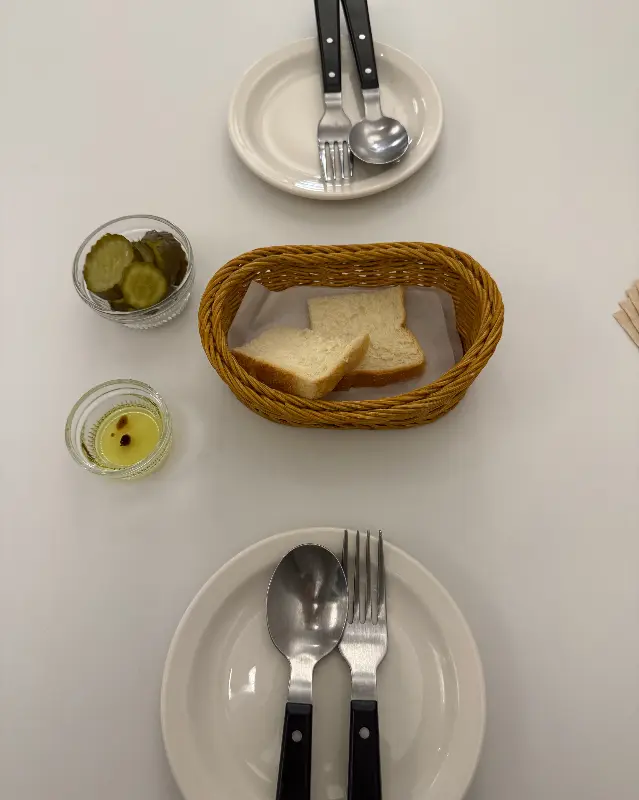 식전빵과 피클, 커트러리가 정갈하게 준비된 테이블 세팅
