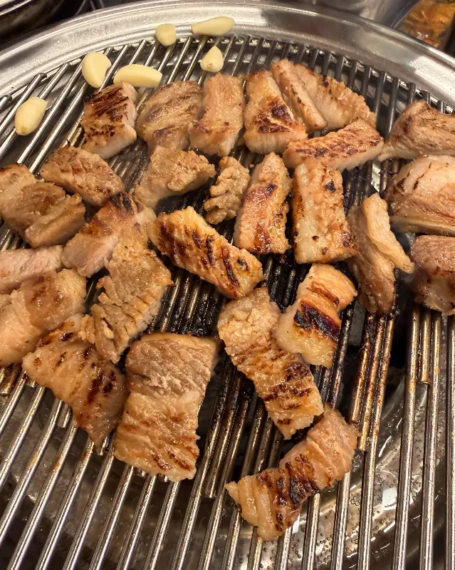 숯불 위에서 익어가는 돼지갈비와 마늘 사진