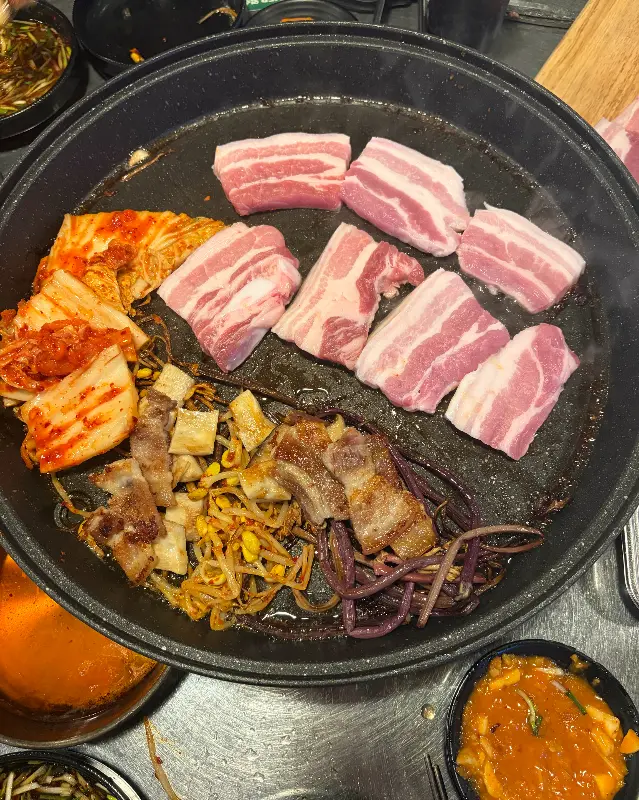 삼겹살과 김치, 콩나물, 고사리를 불판에 올려 굽는 모습