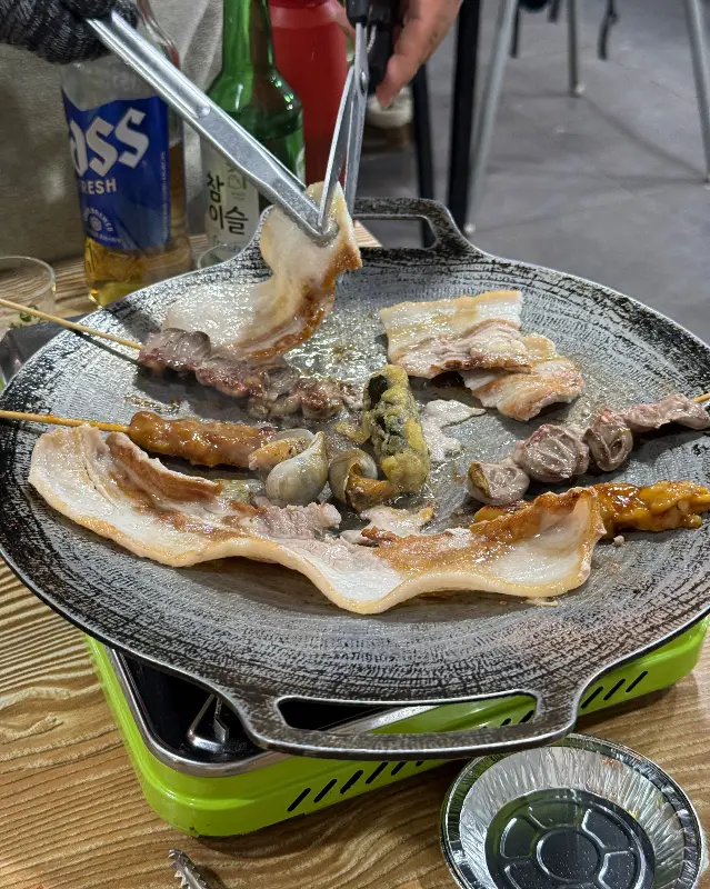 불판 위에서 구워지는 삼겹살과 꼬치