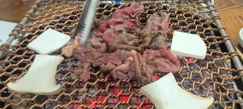 숯불 위 석쇠에 불고기와 큼지막한 새송이버섯이 함께 구워지고 있는 모습