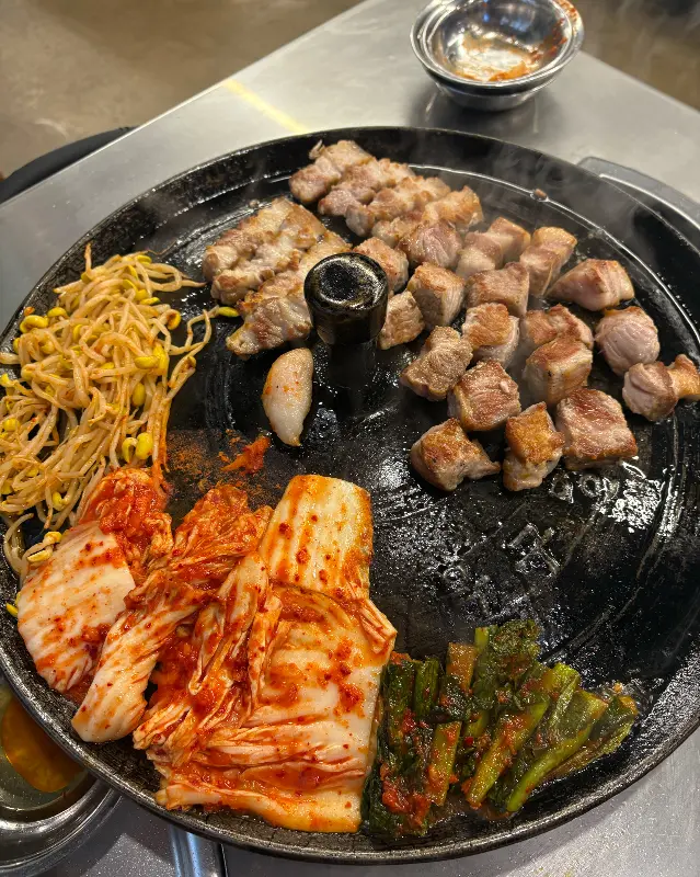 솥뚜껑에 구워진 김치와 콩나물, 삼겹살