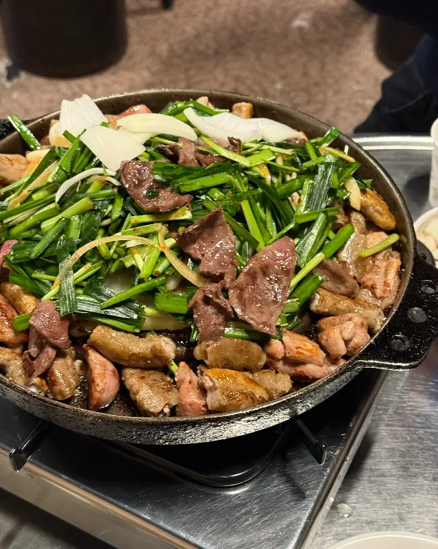 불판 위에 곱창, 막창, 염통, 부추, 양파, 마늘이 푸짐하게 담겨 있는 모습