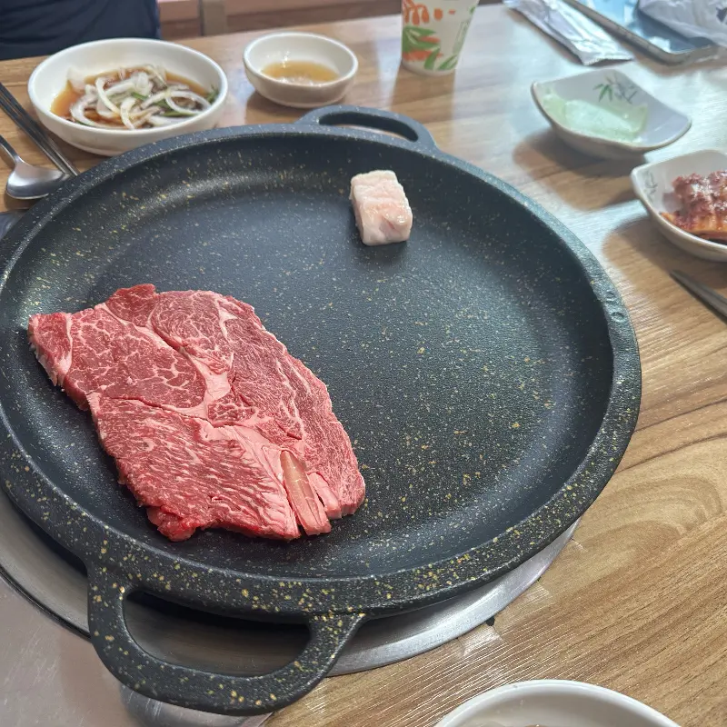 불판 위에 한 점 놓인 한우, 섬세한 마블링이 입맛을 자극한다.
