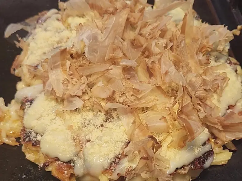 테이블 위 철판에 놓인 치즈 오코노미야끼 클로즈업 사진