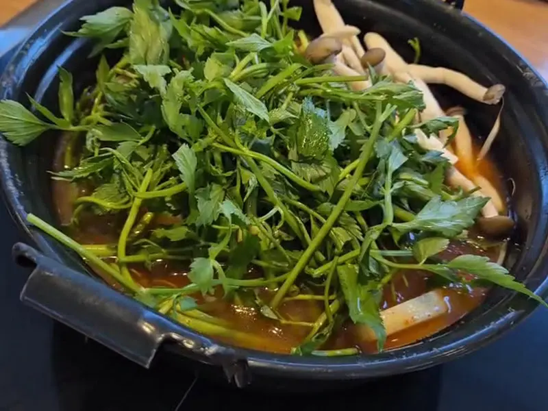 미나리와 숙주, 팽이버섯이 푸짐하게 담긴 샤브샤브 육수