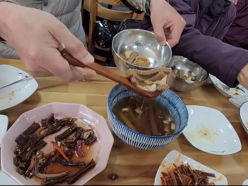 나무 숟가락으로 도토리묵과 야채를 들어올리는 모습