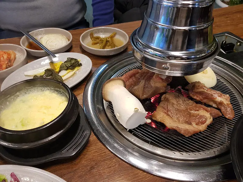 숯불 위에서 구워지는 돼지갈비와 풍성한 밑반찬