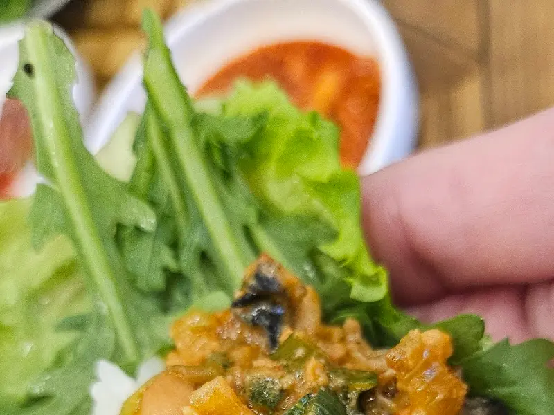 상추에 밥과 우렁쌈장을 올려 쌈을 싸 먹는 모습