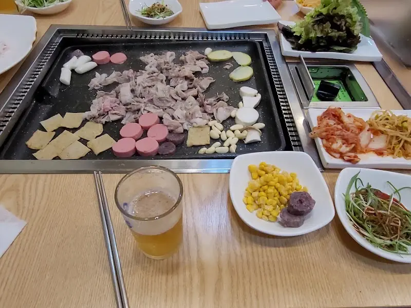 불판 위에 구워진 대패 삼겹살과 다양한 사이드 메뉴