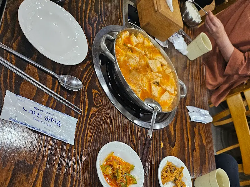 두부찌개가 담긴 뚝배기와 다양한 밑반찬이 놓인 테이블