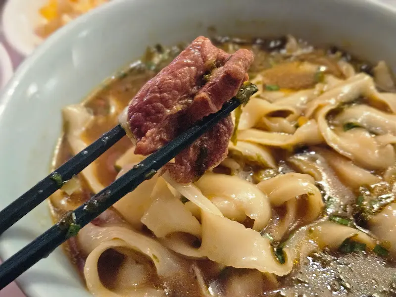 젓가락으로 집어 올린 도삭면과 고기