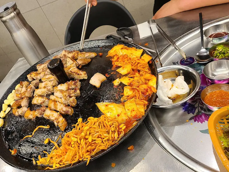 불판 위에 구워진 김치, 콩나물, 미나리