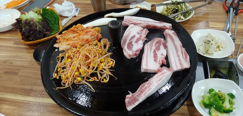 솥뚜껑에 구워지는 삼겹살과 콩나물