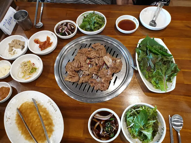 테이블 가득 차려진 돼지갈비 한 상 차림. 푸짐한 쌈 채소와 다양한 밑반찬들이 눈길을 사로잡는다.